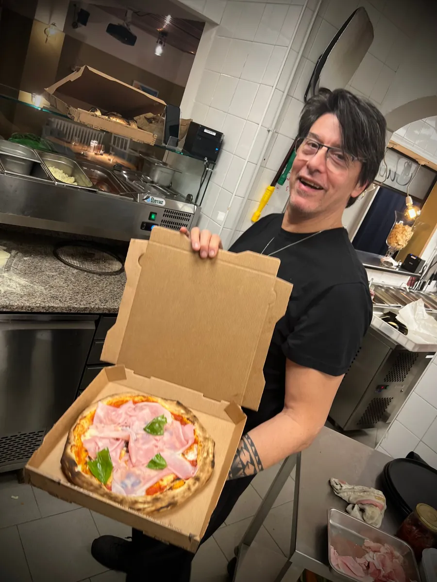 Fabrice présente une pizza à emporter dans sa boîte